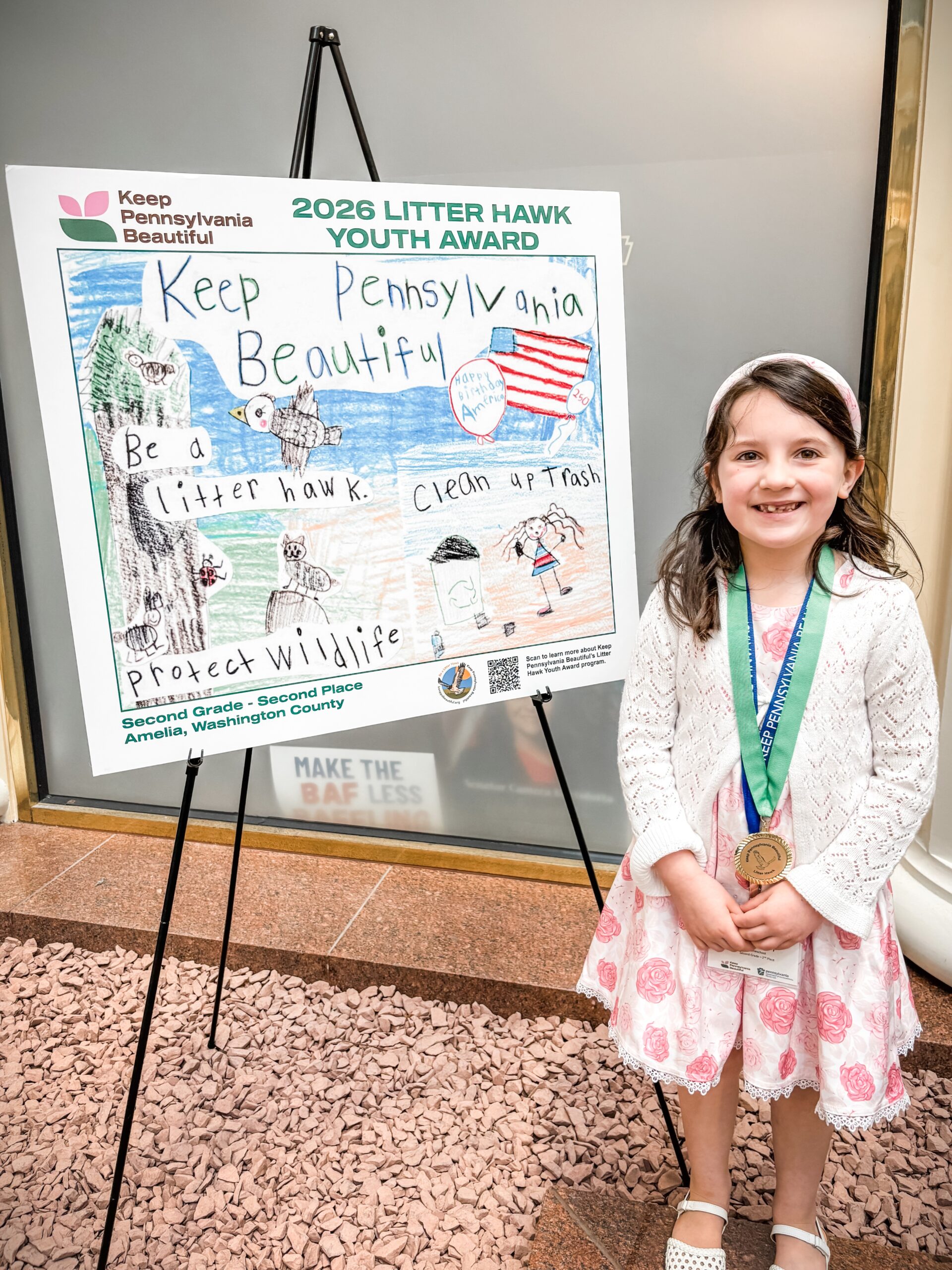 Amelia with her 2026 second place poster in the 2nd grade level.